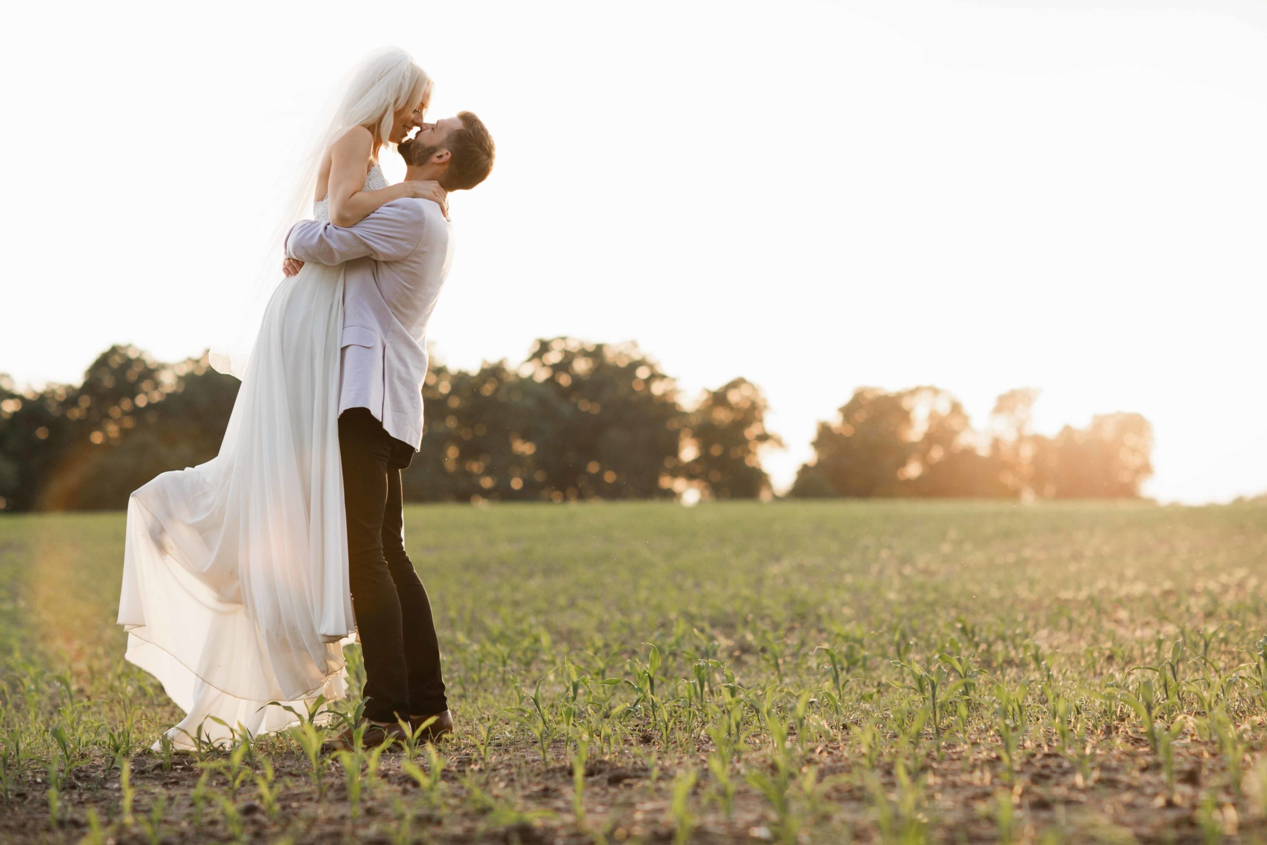 Golden hour in field in Illinois groom lifting bride by Geneva Wedding Photographer