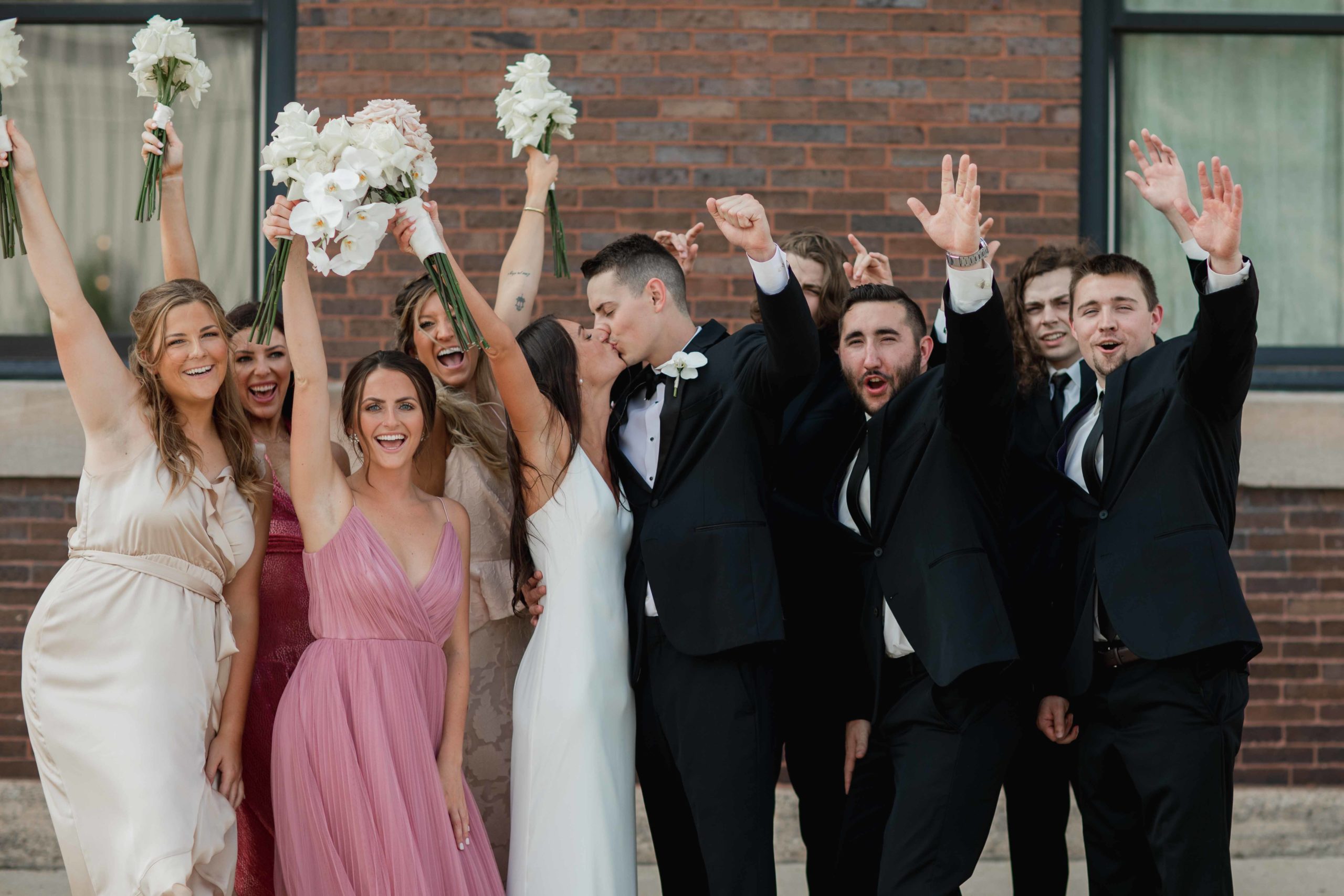 Company 251 Geneva Wedding Photographer bridal party cheering in front of building in Aurora Illinois