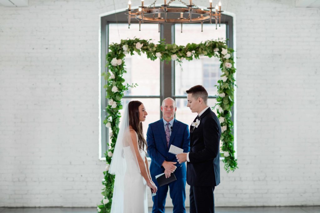 Company 251 Geneva Wedding Photographer bride and groom under floral arch at ceremony